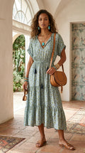 Model wearing sage green floral silk midi dress with tan  bag in courtyard setting