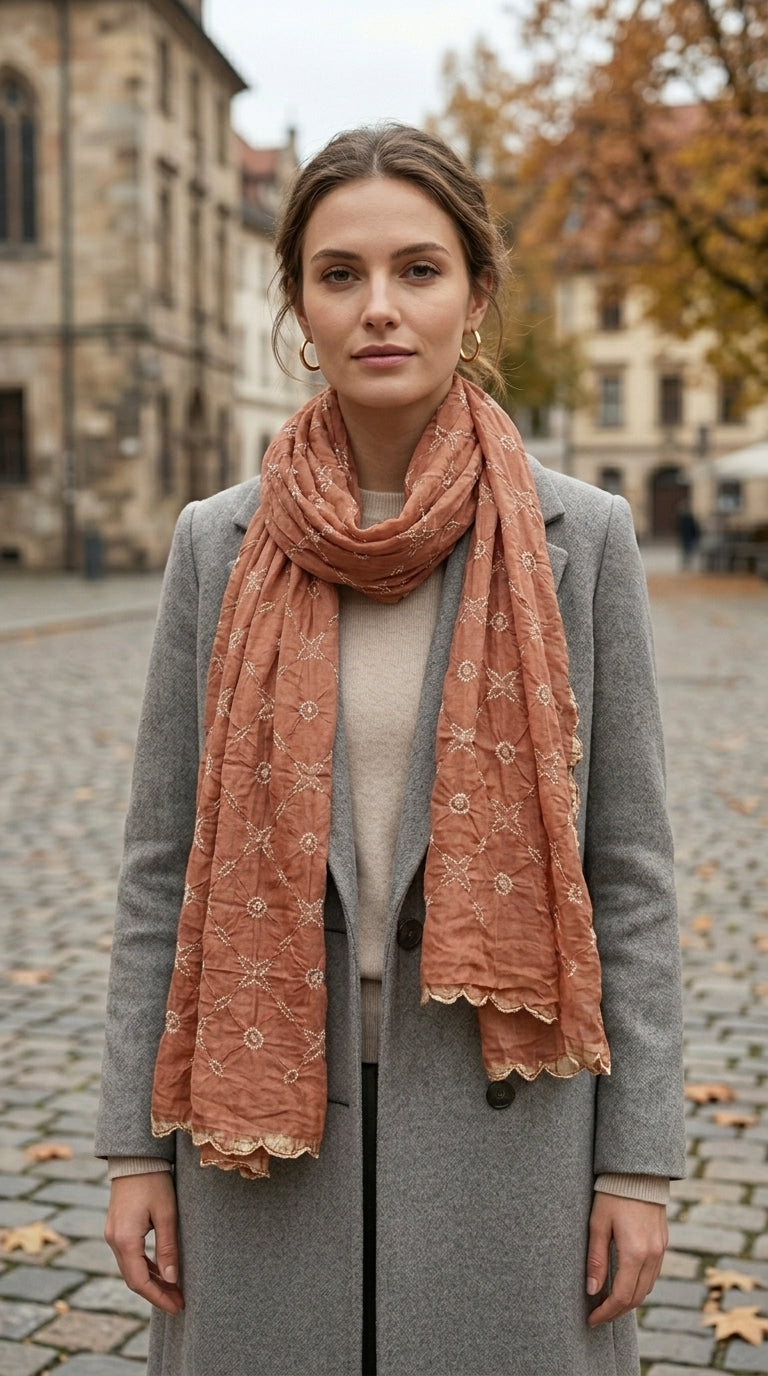 Woman wearing rust orange hand bandhani silk scarf over grey coat on Paris street"