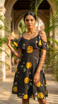 Model wearing yellow floral cold-shoulder resort dress in courtyard setting
